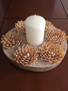 a candle sits on top of a wooden tray with pine cones and leaves around it