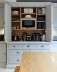 a kitchen with white cabinets and wooden counter tops is shown in this image, there are many appliances on the shelves