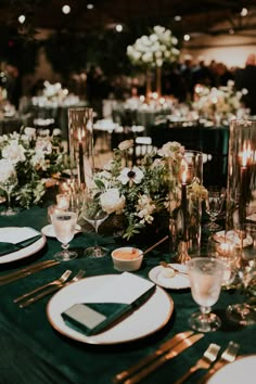 the table is set with plates, silverware and candles for an elegant wedding reception