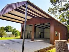 an empty building with a metal roof next to a tree