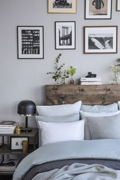 a bed with white sheets and pillows in front of pictures on the wall above it