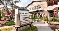 a sign that reads east end market is in front of a building with many plants and trees