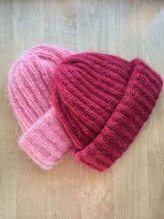 two knitted hats sitting on top of a wooden table