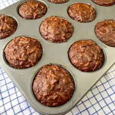 a muffin tin filled with chocolate cupcakes on top of a blue and white towel