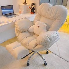 a white chair with a teddy bear on it in front of a laptop and desk