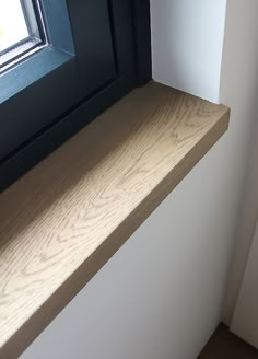 an empty window sill in front of a white wall with black trim on it