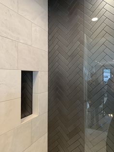 a bathroom with a glass shower door next to a walk in shower and white tiled walls