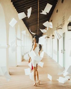 a woman in white dress holding papers flying from her head and standing on the floor