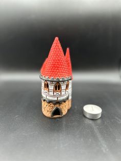 a small red and white building sitting next to a pill bottle on a table top