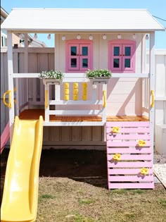 a toy house with a slide and flower boxes on the roof is painted pink and yellow