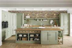 a large kitchen with green cabinets and wooden floors