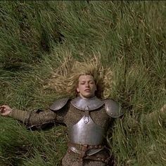 a man laying in the grass with his arms spread out and hands outstretched, wearing armor