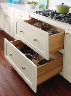 an open drawer in the middle of a kitchen with pots and pans on it