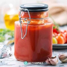 a jar filled with red sauce next to garlic and tomatoes