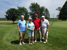 three men and two women standing on a golf course