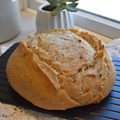 a loaf of bread sitting on top of a black mat next to a potted plant