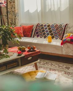 a living room filled with lots of furniture and pillows on top of a rug next to a window