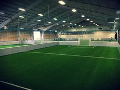 an indoor tennis court with grass and lights