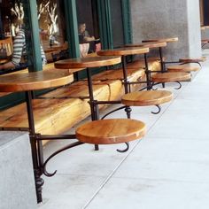 several wooden benches lined up on the side of a building with people sitting at them