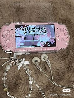 a pink nintendo wii game system sitting on top of a fur covered floor next to ear buds