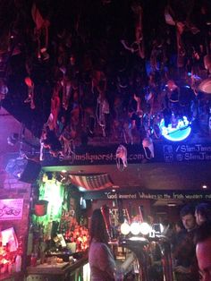 people sitting at tables in a bar with neon lights on the ceiling and signs above them