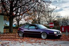 a purple car parked in front of a stop sign