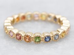 a yellow gold ring with multi colored stones