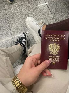 a woman holding a passport in her hand while sitting on the floor at an airport