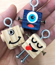 three wooden keychains with faces on them in the palm of someone's hand