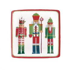 three nutcrackers on a white plate with red trimming and green accents