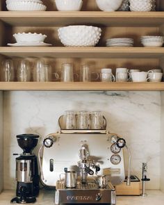 a coffee maker sitting on top of a counter next to cups and bowls in a kitchen