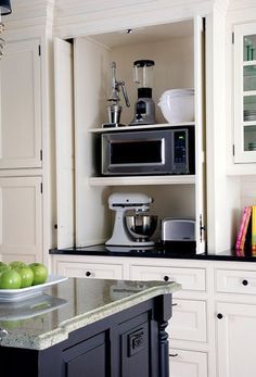 a microwave oven sitting on top of a counter next to an apple and other kitchen items