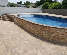 a backyard with a swimming pool surrounded by brick walls and steps leading up to it