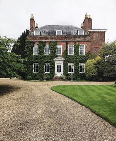 a large brick building with ivy growing on it's sides and two driveways leading to the front door