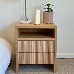 a nightstand with two planters on it next to a bed