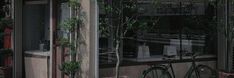 a bicycle is parked in front of a storefront with plants growing on the windows