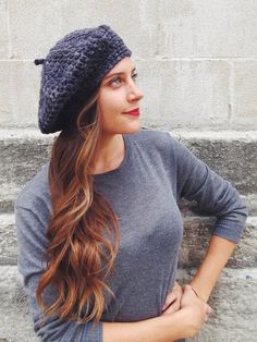 a woman standing in front of some steps wearing a knitted beanie and jeans