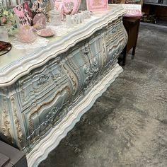 an antique dresser with pink and white decorations on it's sideboard in a store