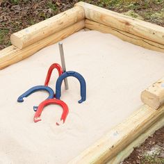 there are two pairs of scissors in the sandbox with some tools on top of it