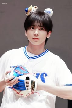 a young man wearing a baseball uniform holding a catchers mitt in his hand