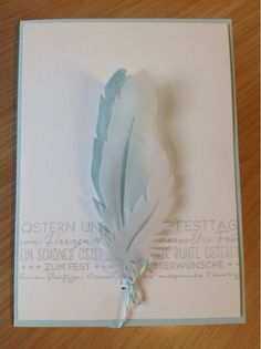 a white card with a blue feather on it