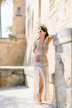 a woman in a dress leaning against a stone wall