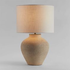 a table lamp with a white shade on it's base and a light bulb in the shape of a vase