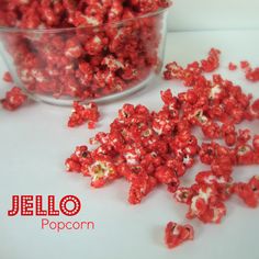 a glass bowl filled with red popcorn sitting on top of a white counter next to it