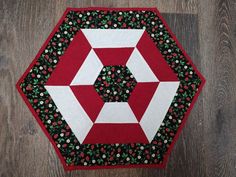 a red and white quilted table topper on a wooden floor