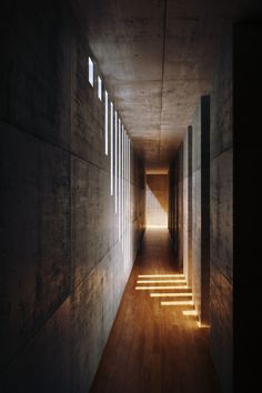 an empty hallway with light coming through the windows and shadows on the wall behind it