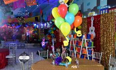 there is a table with many balloons on it in the middle of a room filled with tables and chairs