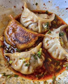 some dumplings are sitting in a bowl with sauce