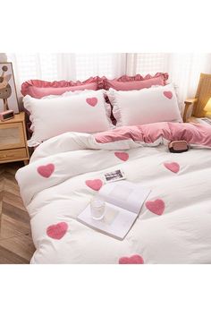 a white bed with pink hearts on it and a cup of coffee in the middle