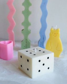 four different colored dices sitting next to each other on a white surface with black dots